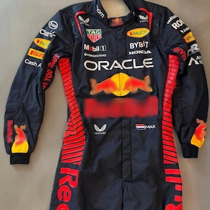 May include: A dark navy racing suit with red and yellow detailing. The suit displays sponsor logos such as "Oracle," "Tag Heuer," and "Esso." The Red Bull logo is on the chest. The suit has long sleeves and a full-length design.