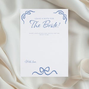 Puede incluir: Una tarjeta blanca con texto azul e ilustraciones de lazos. El texto dice "LEAVE A NOTE FOR The Bride!" y "SHARE YOUR WISHES AND ADVICE FOR THE BRIDE TO BE". La tarjeta también incluye la frase "With love."
