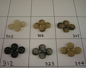 May include: Assortment of round buttons in various colors, including light tan, brown, black, and gray. Each button has four holes and is arranged in groups. The numbers 303, 306, 307, 312, 323, and 304 are visible.