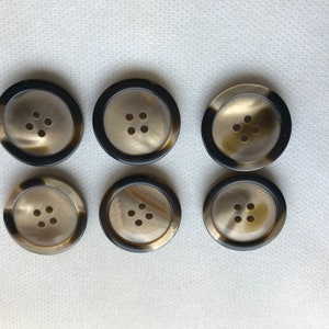 May include: Six round buttons with a tortoiseshell design and four holes each. The buttons have a dark brown outer ring and a light brown center. The buttons are arranged in two rows of three.
