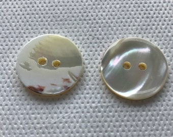 May include: Two round, iridescent mother-of-pearl buttons with two holes each. The buttons have a pearlescent sheen with subtle variations in color, reflecting light. These buttons are ideal for sewing and craft projects.