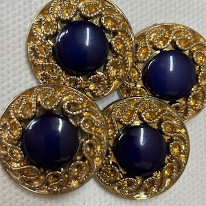 Könnte beinhalten: Vier Vintage-Knöpfe mit einem goldfarbenen Filigranmuster, das einen dunkelblauen, runden Mittelpunkt umgibt. Die Knöpfe sind in einer Gruppe angeordnet und zeigen ihre verzierten Details und Kontrastfarben.
