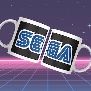 May include: Two white ceramic mugs featuring the SEGA logo in blue and white on a black panel. The mugs are set against a retro-style background with a grid pattern and stars.