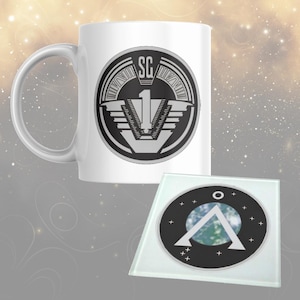 May include: White ceramic mug and glass coaster set. The mug has a black and grey graphic with the letters "SG" and the number "1". The coaster has a black border with a white symbol and a blue and green background.