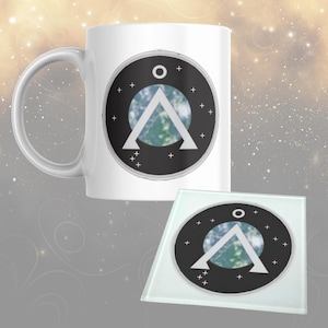 May include: White ceramic mug and square glass coaster set. Both feature a black circle design with a white triangle, a blue and green planet, and white crosses and a circle. The mug has a curved handle.