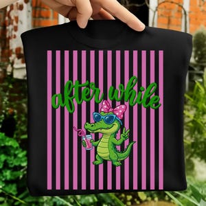 Peut inclure: T-shirt noir avec un fond à rayures roses et noires. Le t-shirt présente un alligator de dessin animé portant des lunettes de soleil et un nœud, tenant une boisson. Les mots "after while" sont écrits en vert.