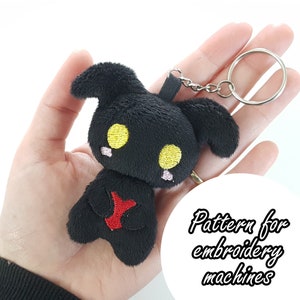 May include: Black plush keychain with yellow eyes and a red heart. Pattern for embroidery machines.