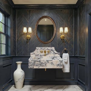 May include: A stylish bathroom featuring a marble sink with gold taps and an oval mirror. The walls are dark blue with a herringbone design, and the floor is marble. A white vase and towel add to the decor. The room has a sophisticated feel.