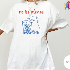 May include: White t-shirt with a blue illustration of a grumpy cat next to a glass of ice cubes. The text "no ice please" is printed in red above the cat and glass. The shirt has short sleeves.