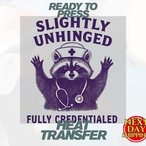 May include: A purple and white heat transfer design featuring a raccoon wearing a nurse's hat and stethoscope. The text reads "READY TO PRESS", "SLIGHTLY UNHINGED", "FULLY CREDENTIALED", and "HEAT TRANSFER". A "NEXT DAY SHIPPING" logo is also present.