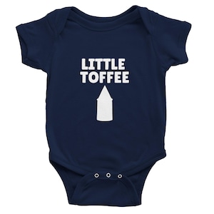 Könnte beinhalten: Marineblauer Baby-Body mit dem weißen Text "LITTLE TOFFEE" über einer weißen Pfeilgrafik. Der Body hat kurze Ärmel und drei Druckknöpfe am unteren Saum.