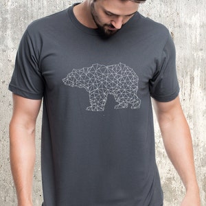 Mens short sleeve graphic tee shirt in charcoal gray with a graphic print of a bear shape depicted in miniature triangles. The t shirt is shown on a manis figure from the lower face to upper hips so you can see the classic fit of the t-shirt.