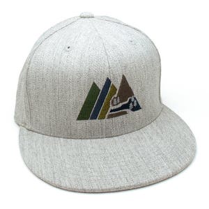 May include: A grey and white baseball cap with a mountain range design embroidered on the front. The mountains are green, brown, and blue.