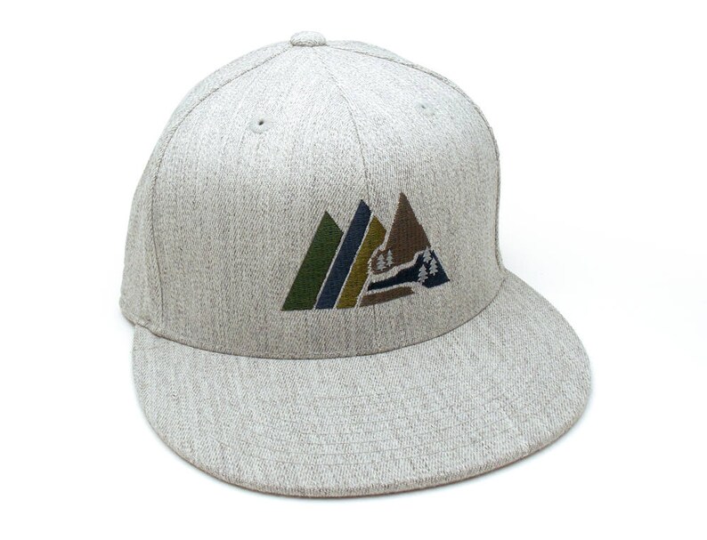 May include: A grey and white baseball cap with a mountain range design embroidered on the front. The mountains are green, brown, and blue.