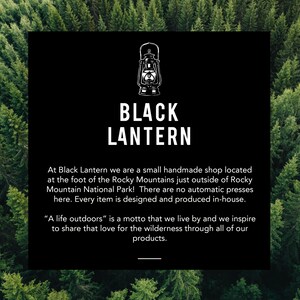 May include: Black Lantern, a small handmade shop located at the foot of the Rocky Mountains, creates unique items. The text "A life outdoors" is a motto that inspires a love for the wilderness.