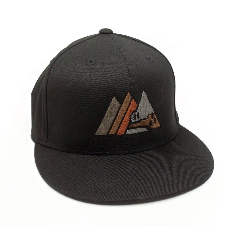 May include: Black fitted baseball cap with an embroidered design of three mountains in shades of brown, orange, and grey. The mountains have a stylised tree and a small cabin in the centre.