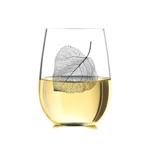 May include: A clear glass wine glass with a delicate, black leaf design on the side. The glass is filled with a pale yellow liquid.
