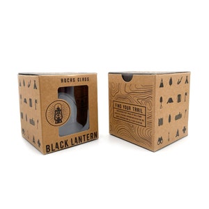 Two whiskey tumblers fitting neatly inside a specially designed Black Lantern retail packaging box shown at different angles, both front and back side views.