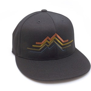 May include: Black baseball cap with a flat brim. The cap features an embroidered mountain range design in shades of gold, copper, and blue. The hat is made of a durable fabric and has a structured fit, suitable for outdoor activities or casual wear.