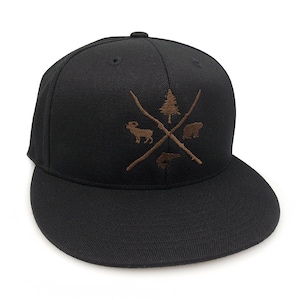 May include: Black baseball cap with a brown embroidered design featuring a tree, a ram, a bear, and a fish.