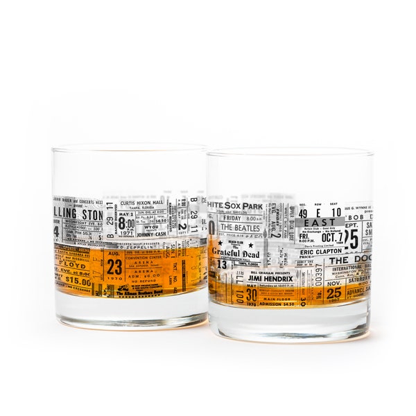 May include: Two clear glass tumblers with a vintage concert ticket design. The glasses feature black and white text with orange and yellow accents. The text includes the names of famous musicians such as The Beatles, Jimi Hendrix, and Eric Clapton.