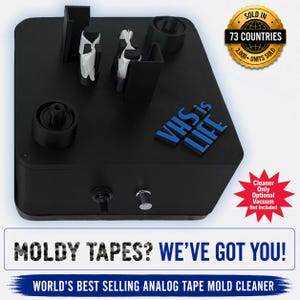 May include: A black rectangular VHS tape mould cleaning device featuring a blue raised logo that reads VHS is LIFE. The unit includes a top-mounted spindle and guide mechanism, a front toggle switch, and a silver button. Text states MOLDY TAPES? WE'VE GOT YOU!
