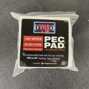 Puede incluir: Un paquete de toallitas no abrasivas PEC PAD, 10 x 10 cm, para limpiadores de cintas VHS. La etiqueta presenta el texto "VHS is life" y "100 Wipes". Fabricado en EE. UU.