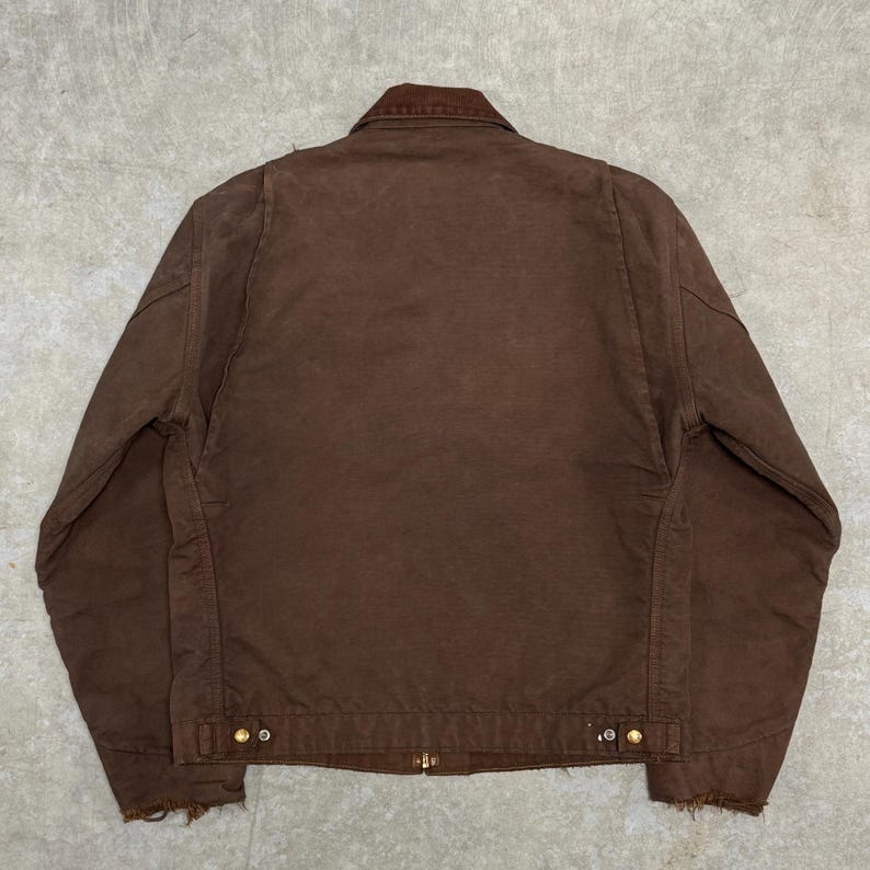 Puede incluir: Chaqueta de trabajo marr&oacute;n con cuello de pana. La chaqueta tiene cierre de botones, dos bolsillos delanteros y un dobladillo desgastado. Fabricada con un material duradero, es adecuada para actividades al aire libre.