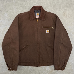 Puede incluir: Chaqueta Carhartt marr&oacute;n con cuello de pana y cremallera dorada. La chaqueta tiene dos bolsillos delanteros y un peque&ntilde;o parche con el logotipo en el pecho. Fabricada con un material duradero, est&aacute; dise&ntilde;ada para el trabajo.