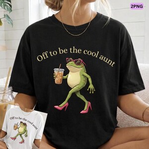 May include: Black t-shirt with the phrase "Off to be the cool aunt" in gold lettering. The shirt features a cartoon frog wearing sunglasses and high heels, holding a beverage with ice.