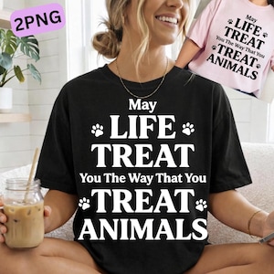Puede incluir: Camiseta negra con el texto "May Life Treat You The Way That You Treat Animals" en blanco. En el fondo se ve una camiseta rosa con el mismo texto. Las camisetas son ropa informal.