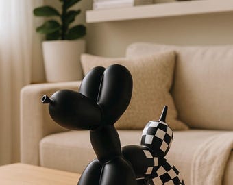 May include: A black balloon dog sculpture with a checkered pattern on the rear. The sculpture is on a wooden table in front of a beige sofa. The dog is a whimsical decorative item.
