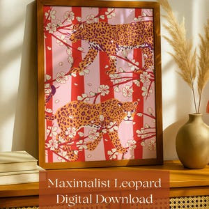 Könnte beinhalten: Ein gerahmter Kunstdruck mit zwei Leoparden mit orangefarbenen und schwarzen Flecken, vor einem rosa-rot gestreiften Hintergrund mit weißen floralen Akzenten. Der Druck befindet sich in einem braunen Holzrahmen. Der Text auf dem Druck lautet "Maximalist Leopard Digital Download."