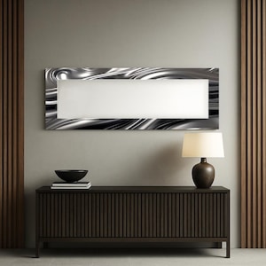 Peut inclure: Intérieur moderne avec une console en bois foncé, un bol noir et des livres. Au-dessus, une œuvre d'art murale rectangulaire avec un motif argenté ondulé et un centre blanc. Une lampe marron est posée sur la console.