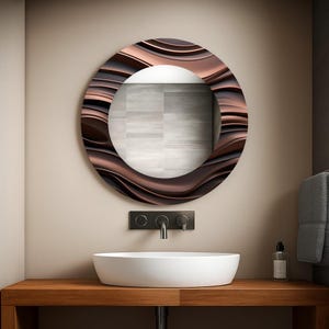 Pode incluir: Um espelho redondo, cor de bronze, com uma moldura ondulada e texturizada, está pendurado acima de uma pia oval branca. O espelho está montado numa parede bege, e a pia assenta numa bancada de madeira. Uma torneira preta e um dispensador de sabonete também são visíveis.