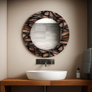 Könnte beinhalten: Ein runder Spiegel mit einem dekorativen Holzrahmen mit einem geometrischen Muster. Der Rahmen ist eine Kombination aus Dunkelbraun und Schwarz. Der Spiegel ist über einem weißen, ovalen Waschbecken und einer Holz-Arbeitsplatte montiert.