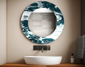 May include: A round wall mirror with a dark teal and white abstract design around the edge. The mirror is mounted above a white sink and a wooden countertop. The faucet and hardware are black.
