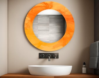 May include: A round orange and yellow decorative mirror with a marbled design hangs above a white sink. The mirror is mounted on a light beige wall. The sink sits on a wooden countertop.