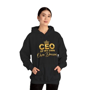 May include: Black hooded sweatshirt featuring a gold crown and the words "CEO of My Own Dreams". The sweatshirt has a front pocket and a drawstring hood. The design is centered on the chest.