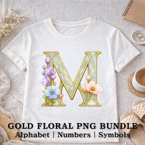 Puede incluir: Camiseta blanca con una letra "M" dorada, con interior azul claro y adornada con flores moradas, azules y melocotón. El texto "GOLD FLORAL PNG BUNDLE" está en la parte inferior, con "Alphabet | Numbers | Symbols".