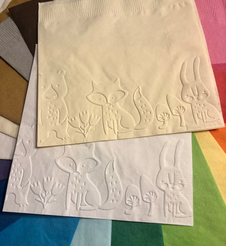 Puede incluir: Dos servilletas de papel blancas con dise&ntilde;os en relieve de animales del bosque. La servilleta superior presenta un oso, un zorro y un conejo, mientras que la servilleta inferior presenta un zorro, un conejo y setas.