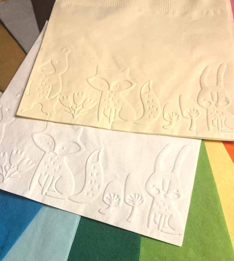 Puede incluir: Dos servilletas de papel blancas con dise&ntilde;os en relieve de animales del bosque. La servilleta superior presenta un conejo, un zorro y dos setas. La servilleta inferior presenta un zorro, un conejo y dos setas.