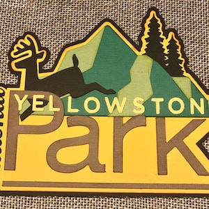 May include: Yellowstone National Park logo with a black silhouette of a deer jumping in front of a green mountain range with a yellow and green forest. The text "Yellowstone National Park" is in yellow letters on a green background.