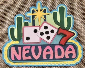 May include: A colorful paper craft with a retro Vegas sign design. It features a pair of dice, a number seven, and the word "NEVADA" in pink letters.