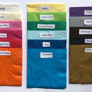 Pu&ograve; includere: Una collezione di tovaglioli di carta piegati in vari colori, tra cui bianco, avorio, rosa, rosso, arancione, giallo, verde, blu, turchese, viola, argento, marrone, nero e oro. Ogni colore &egrave; etichettato.