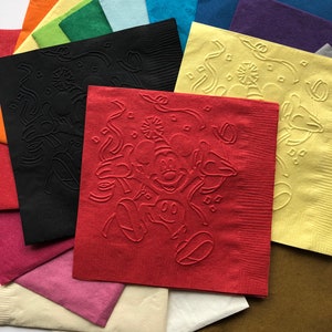 Pu&ograve; includere: Una collezione di tovaglioli di carta colorati in varie tonalit&agrave;, tra cui rosso, nero, giallo e verde. Il tovagliolo rosso presenta un disegno in rilievo di Mickey Mouse. Altri tovaglioli hanno motivi in rilievo.