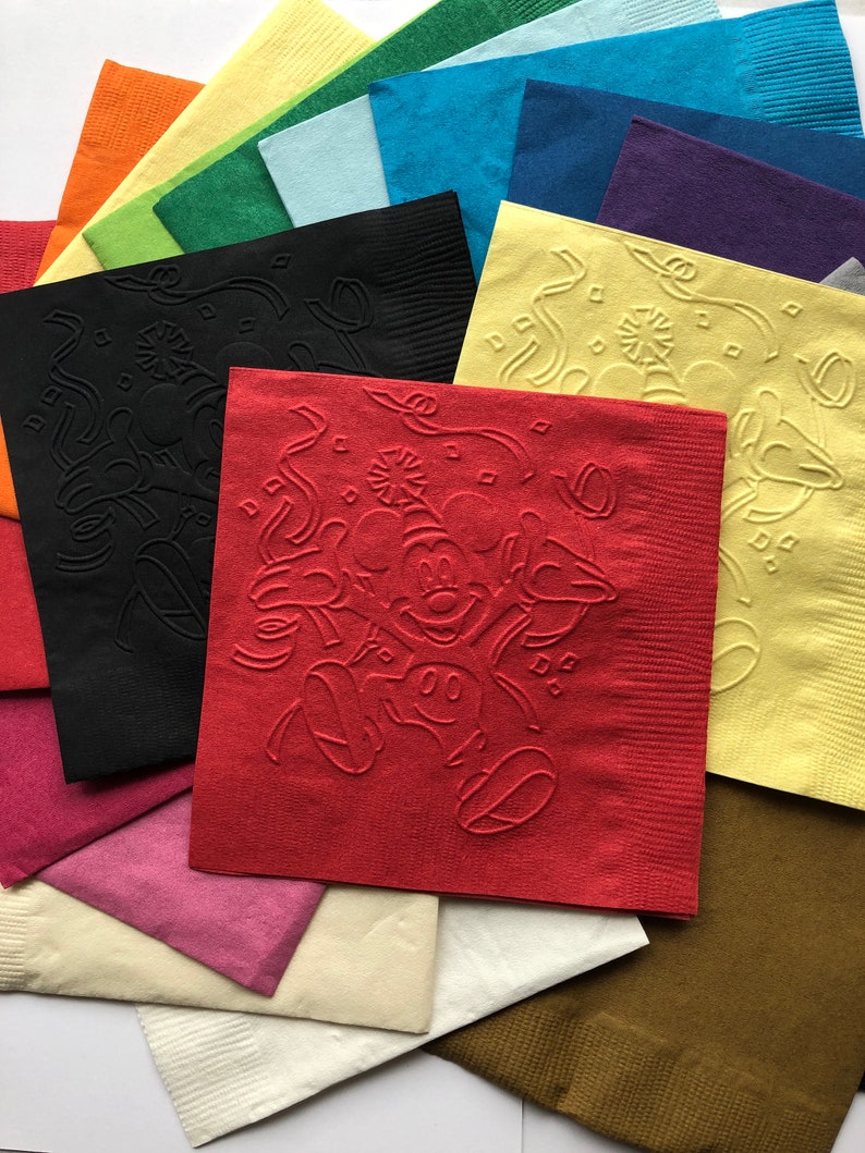 Pu&ograve; includere: Una collezione di tovaglioli di carta colorati in varie tonalit&agrave;, tra cui rosso, nero, giallo e verde. Il tovagliolo rosso presenta un disegno in rilievo di Mickey Mouse. Altri tovaglioli hanno motivi in rilievo.