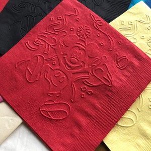 Pu&ograve; includere: Una collezione di tovaglioli di carta colorati, tra cui rossi, neri, gialli e blu. Il tovagliolo rosso presenta un disegno in rilievo di un personaggio dei cartoni animati. I tovaglioli sono quadrati e hanno una superficie strutturata.