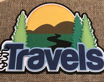 May include: A blue and white paper craft with the text "Our Travels" and a scenic landscape with a sun, mountains, trees, and a river.