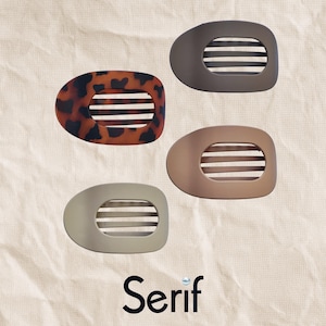 May include: Four oval hair clips with horizontal slats. One clip features a brown and black tortoiseshell pattern, while the others are solid matte colors in dark gray, light brown, and beige. The word Serif is printed in black at the bottom.